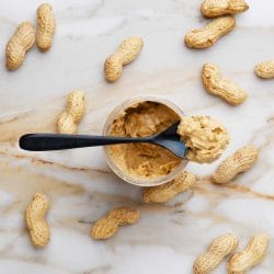 Nut butters: a jar of peanut butter surrounded with whole peanut pods