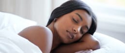 Woman, sleeping peacefully in bed in natural light.